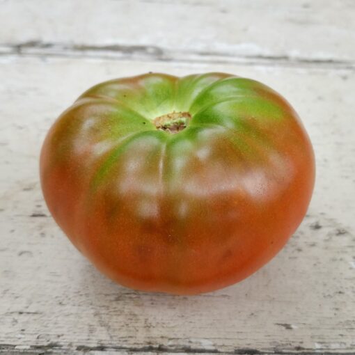 Tomato Black Krim sitting on a white wood surface.