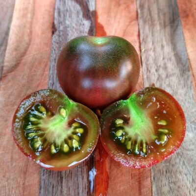 A sliced juicy Black Cherry Tomato on a cutting board.