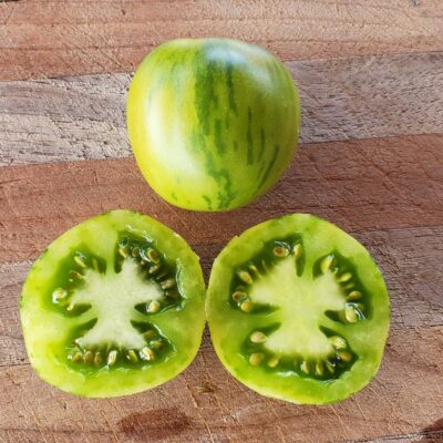 Juicy green vernissage tomato sliced open on a wooden cutting board.