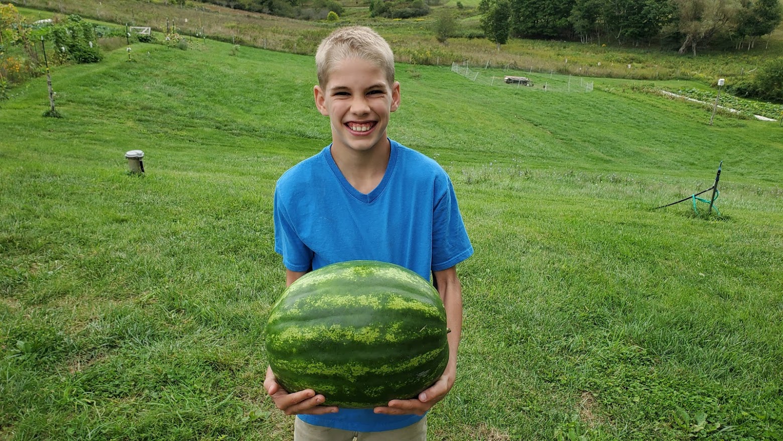 Holding a large Heirloom Watermelon in both arms.