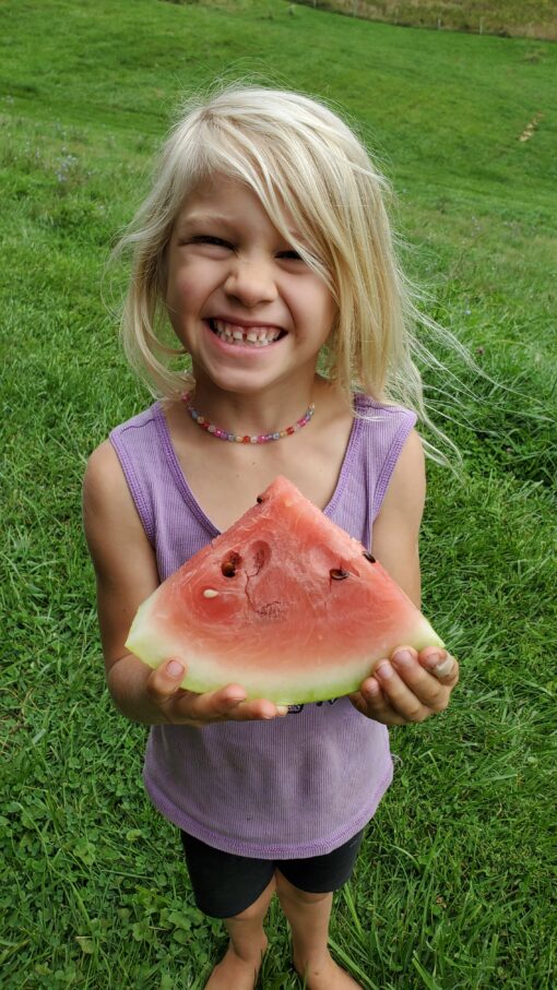 Annalea holding a slice of Crimson Sweet Watermelon.