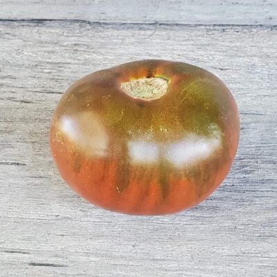 Paul Robeson Tomato sitting on a wooden surface.