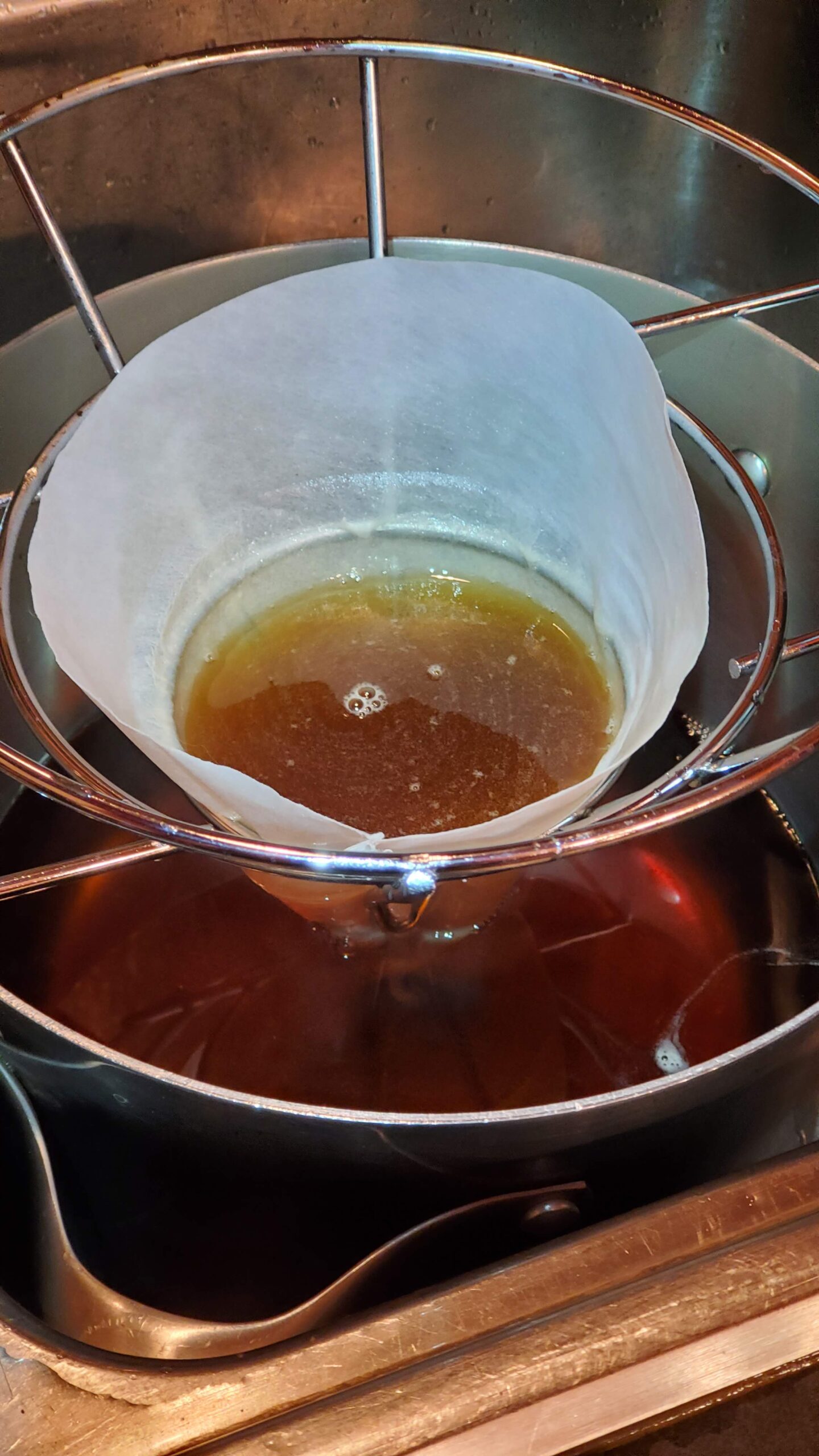 A filter with brown liquid in a metal holder.