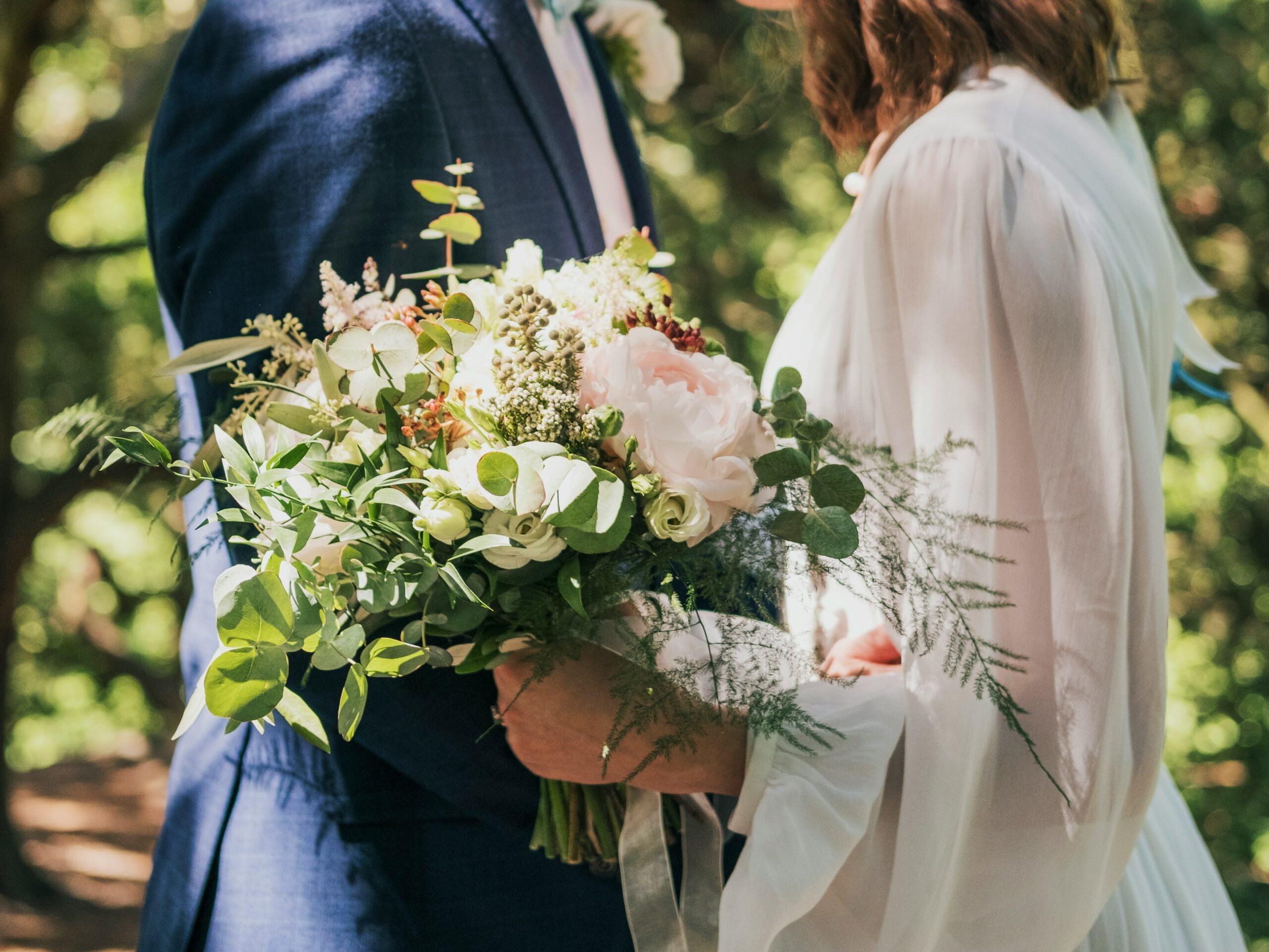 A couple stands close together, partial view of a bouquet between them, with the bottom half of the image obscured by a visual distortion.
