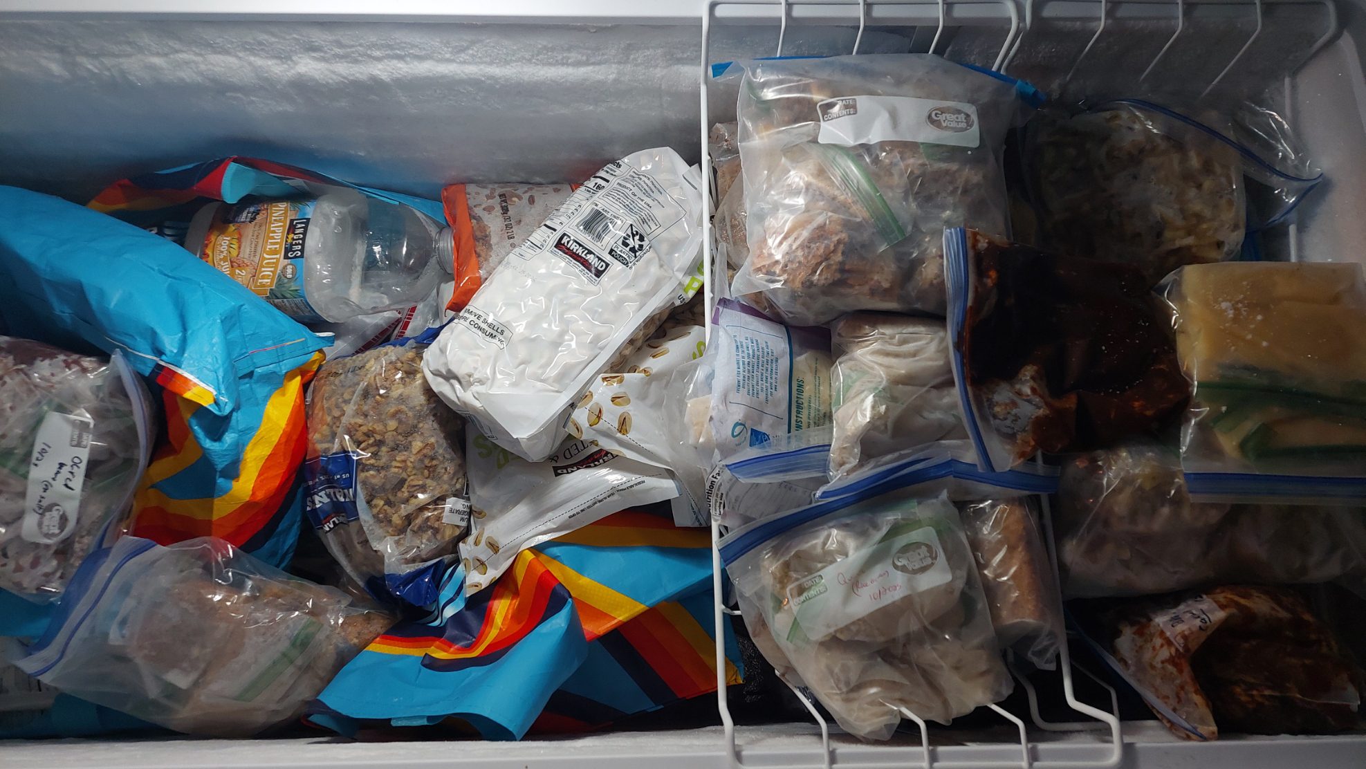 Organizing a freezer filled with various food items in plastic bags and labeled containers, including frozen meats, vegetables, and prepared meals, is essential for maintaining an efficient canning room.